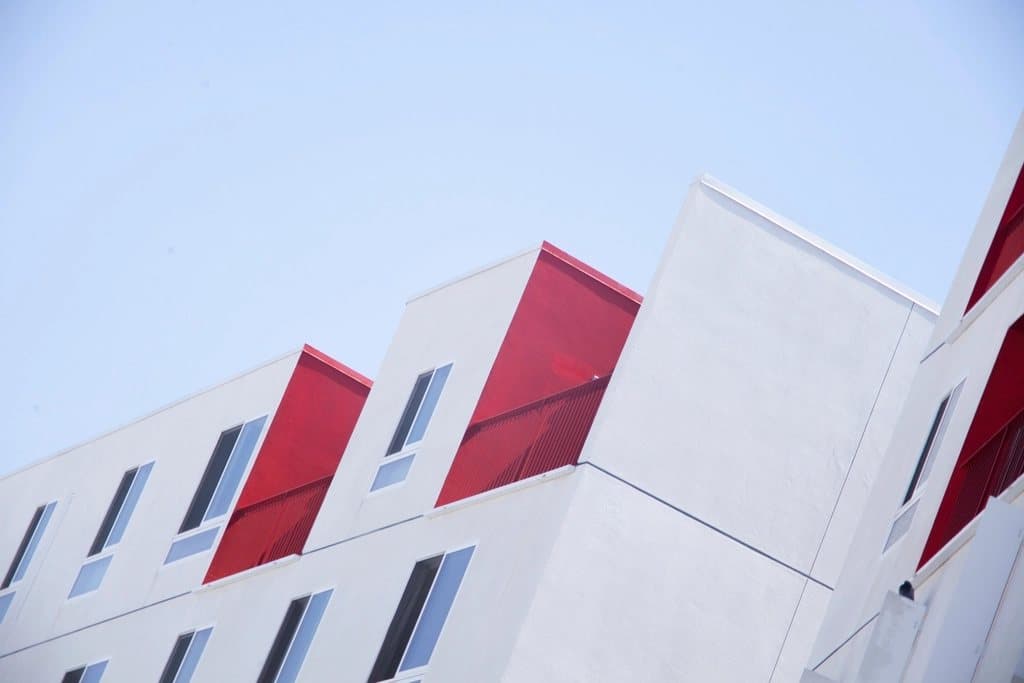 Modern apartment block with white and red facade panels against a blue sky