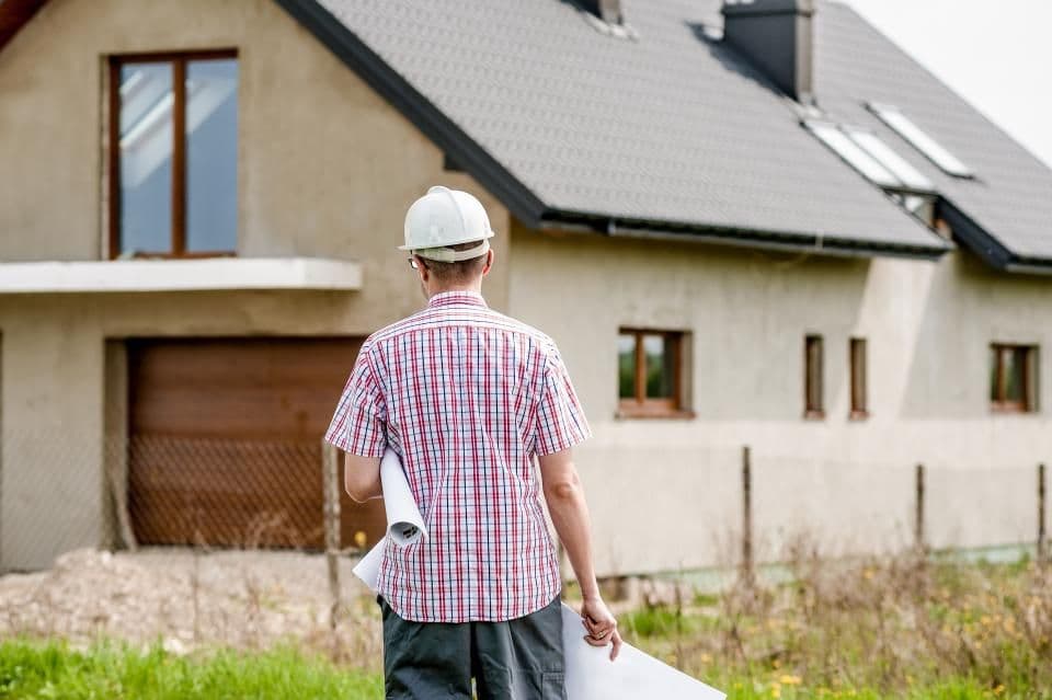 Engineer in a hard hat inspecting a house under construction