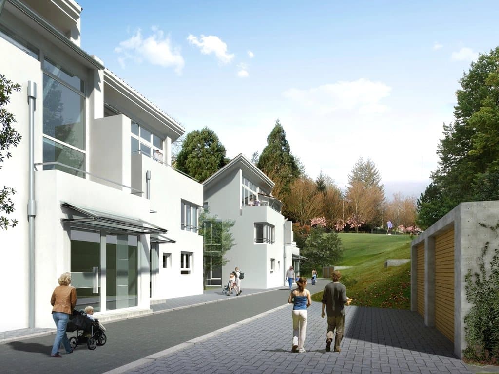 Row of modern white townhouses along a paved, tree-lined lane